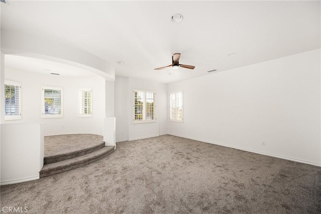 empty room featuring ceiling fan, carpet floors, visible vents, and baseboards