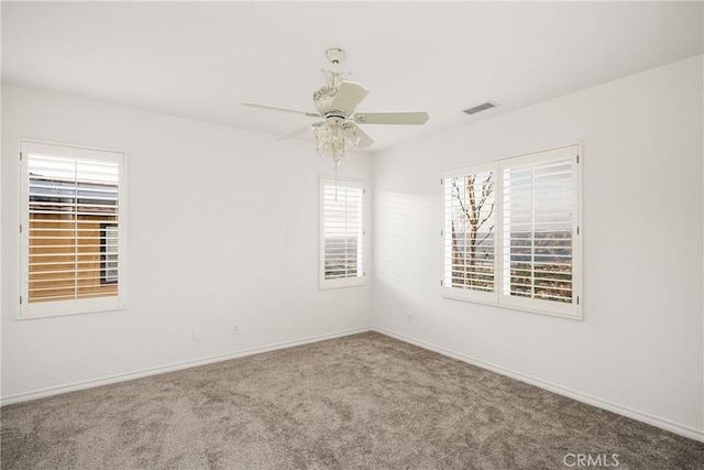 carpeted empty room featuring baseboards, visible vents, and a ceiling fan