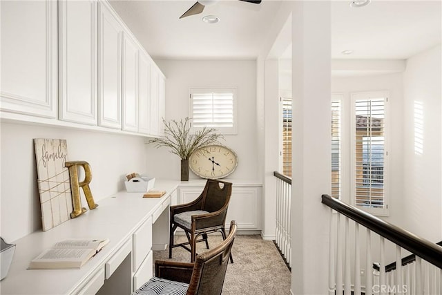 office with built in study area, a ceiling fan, and light colored carpet