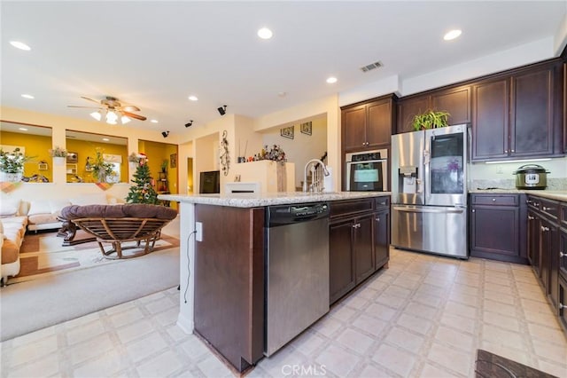 kitchen featuring sink, stainless steel appliances, ceiling fan, an island with sink, and dark brown cabinetry