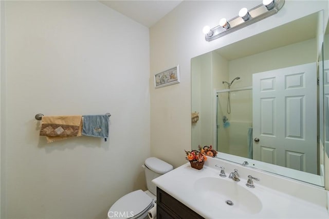 bathroom featuring toilet, a shower with door, and vanity