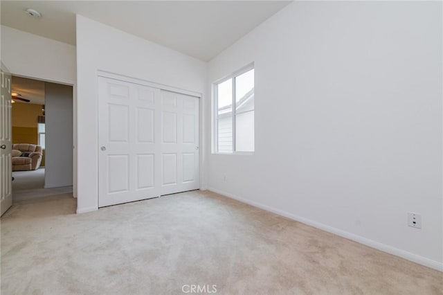 unfurnished bedroom featuring a closet and light colored carpet