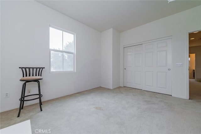 unfurnished bedroom featuring a closet and light colored carpet