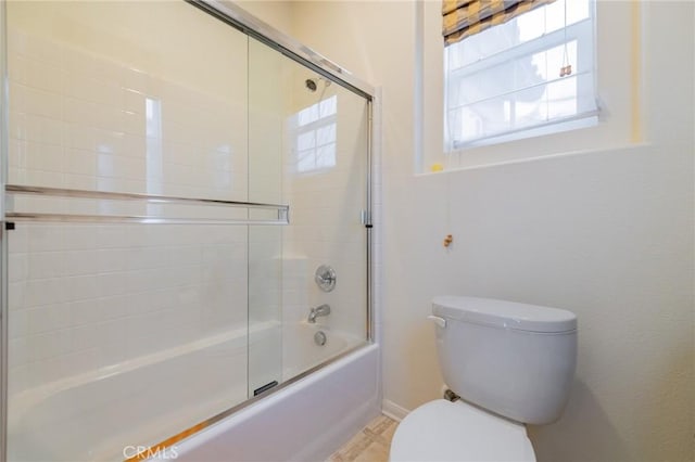 bathroom with combined bath / shower with glass door and toilet