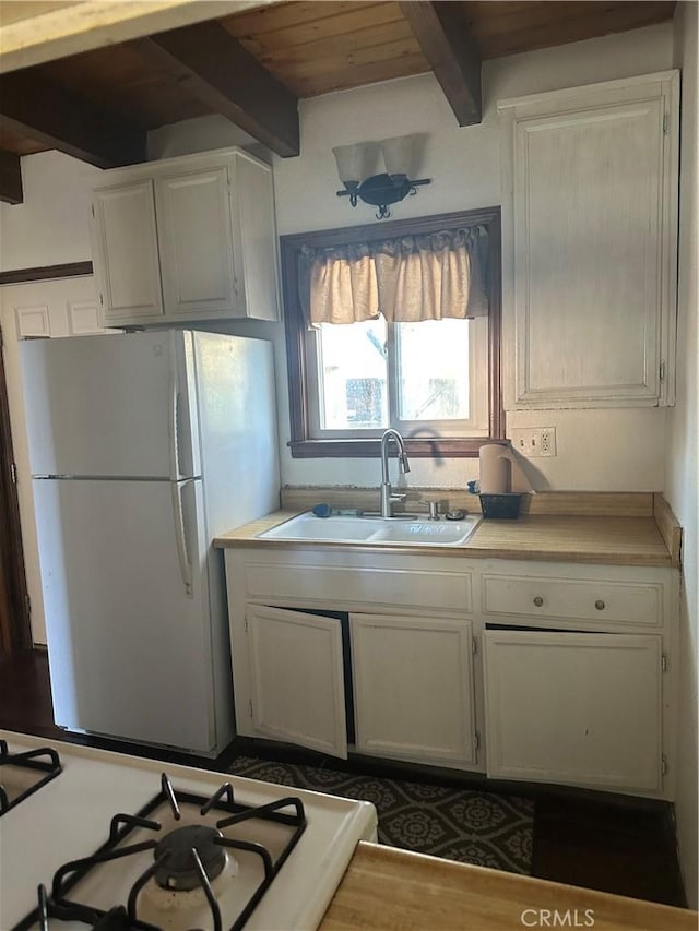 kitchen featuring sink, white appliances, white cabinetry, and beam ceiling