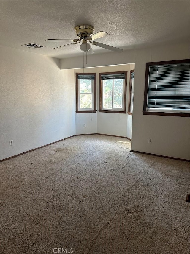 empty room featuring ceiling fan, carpet floors, and a textured ceiling