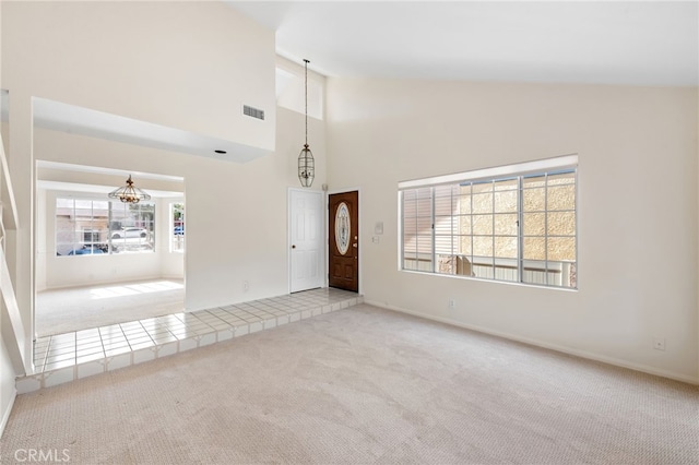 interior space with light carpet, an inviting chandelier, visible vents, and high vaulted ceiling