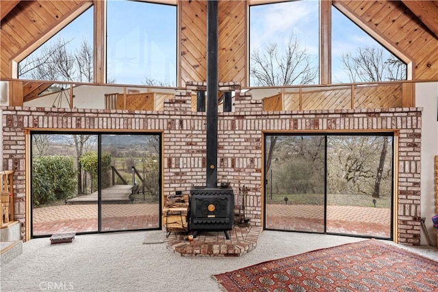 unfurnished living room with carpet floors, a wood stove, and a high ceiling