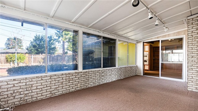 unfurnished sunroom with vaulted ceiling and rail lighting