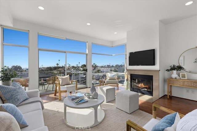 living area featuring a glass covered fireplace, recessed lighting, and wood finished floors