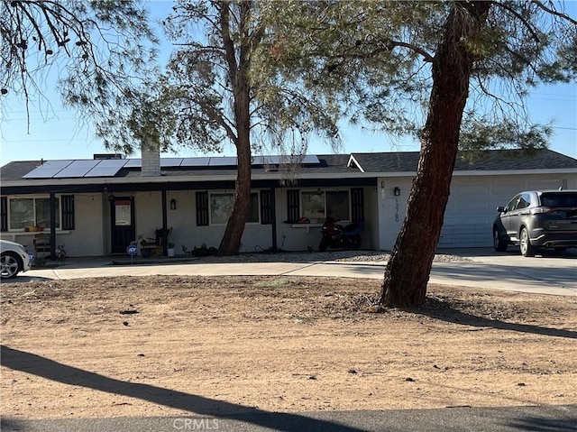 ranch-style home featuring a garage and solar panels