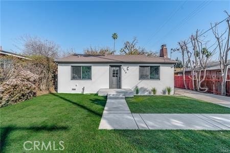 ranch-style home with a front lawn, fence, a chimney, and stucco siding