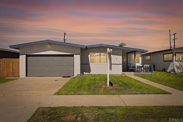 view of front of home with a porch, concrete driveway, an attached garage, a front yard, and fence