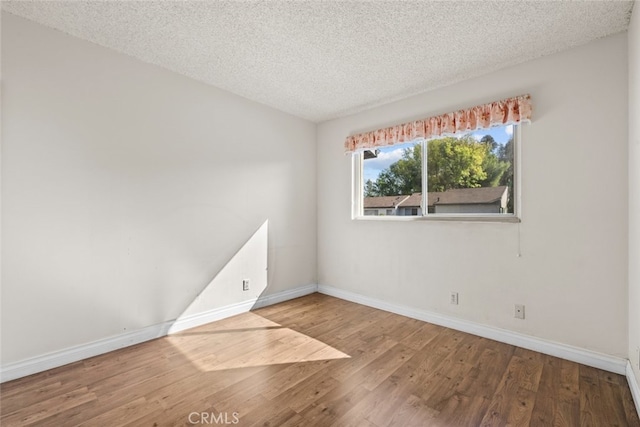 spare room featuring wood-type flooring and a textured ceiling