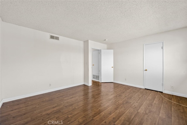 empty room featuring a textured ceiling and dark hardwood / wood-style floors