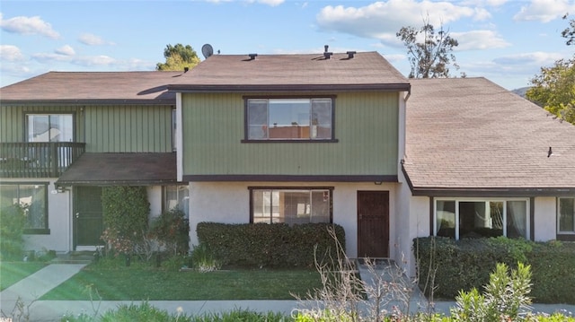 view of front of house featuring a balcony and a front lawn