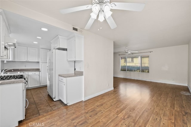 kitchen with white cabinets, ceiling fan, hardwood / wood-style floors, and stainless steel gas range