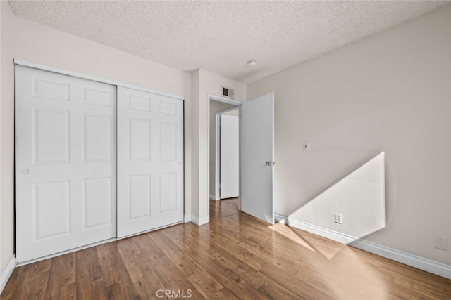 unfurnished bedroom with a closet, wood-type flooring, and a textured ceiling