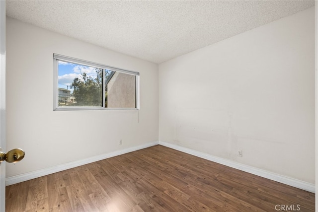 empty room featuring a textured ceiling and dark hardwood / wood-style floors