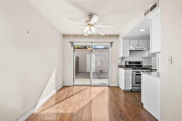 kitchen with white cabinetry, dark wood-type flooring, gas range, and ceiling fan