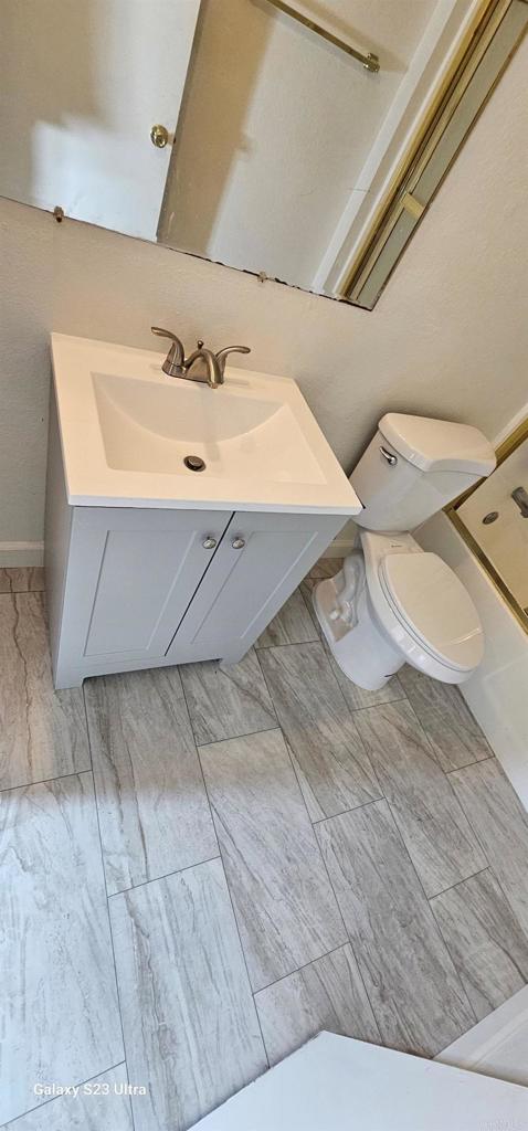 full bathroom featuring toilet, walk in shower, and vanity