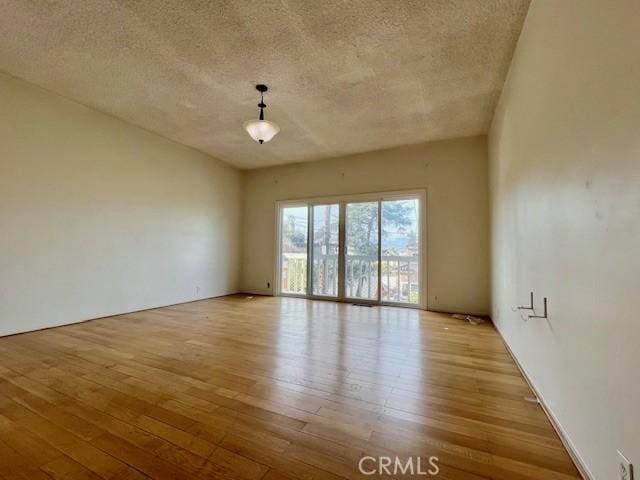 empty room with light wood-type flooring and a textured ceiling