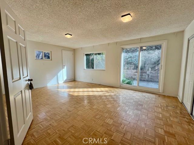 unfurnished room with light parquet flooring and a textured ceiling