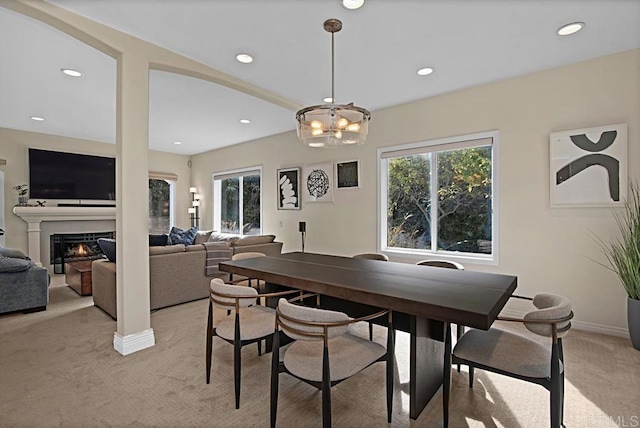 carpeted dining area with a notable chandelier and a healthy amount of sunlight