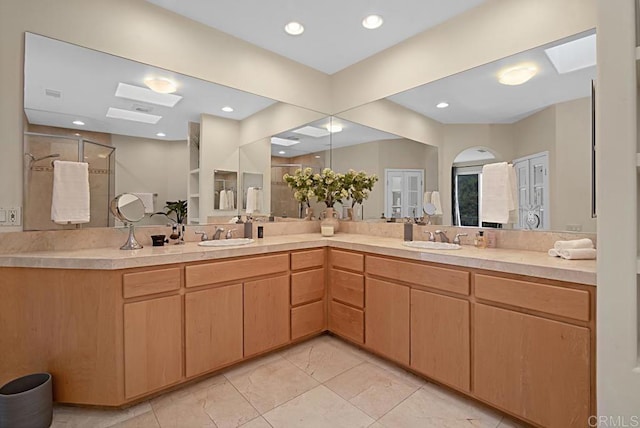 bathroom with a skylight, vanity, and a shower with door