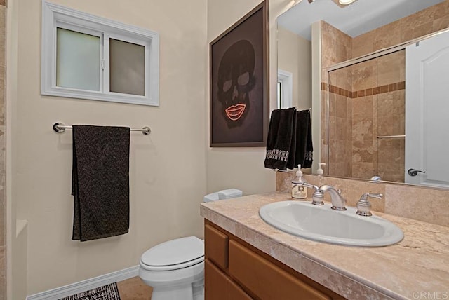 bathroom featuring a tile shower, vanity, and toilet