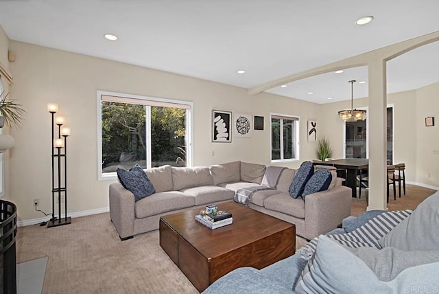 living room with beamed ceiling, a chandelier, and light colored carpet