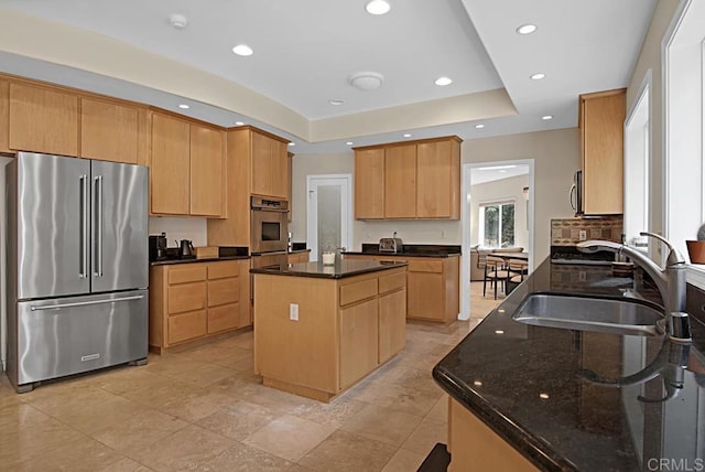 kitchen featuring dark stone countertops, a center island, sink, a raised ceiling, and appliances with stainless steel finishes