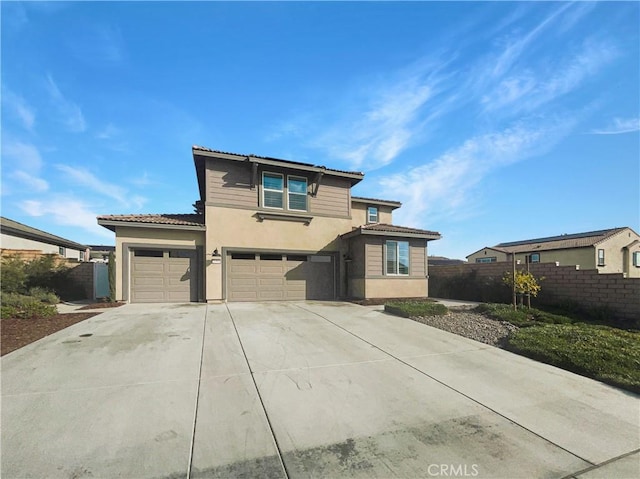 traditional home featuring a garage, driveway, fence, and stucco siding