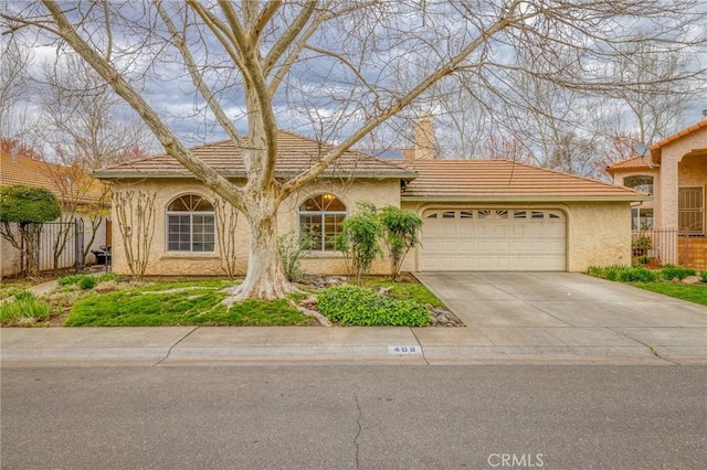 view of front facade featuring stucco siding, driveway, fence, an attached garage, and a tiled roof