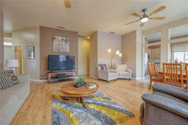 living room with visible vents, light wood-style flooring, and a ceiling fan