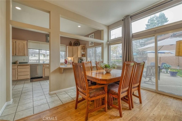 dining space with a wealth of natural light, baseboards, and light wood-style floors