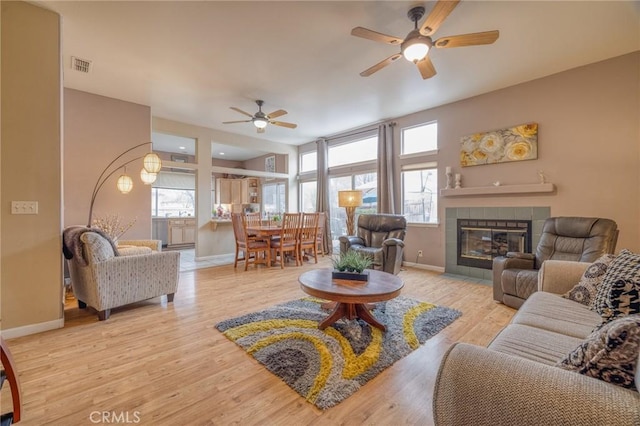 living room featuring a fireplace, wood finished floors, visible vents, and baseboards