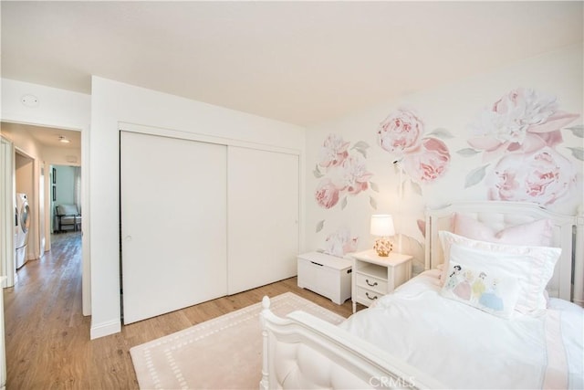 bedroom with a closet, washer / dryer, and light hardwood / wood-style floors