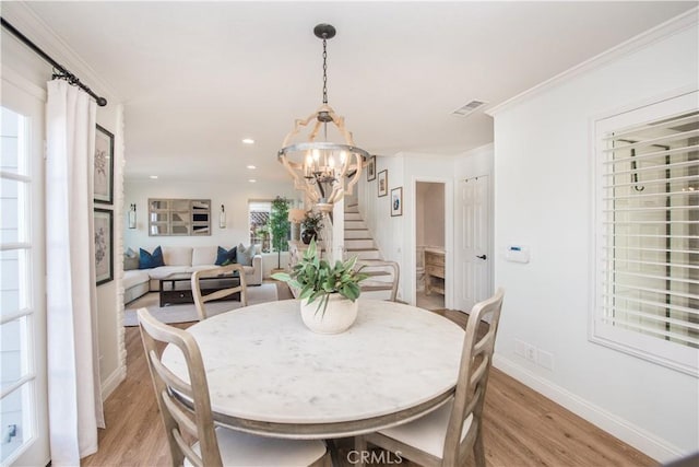 dining area with ornamental molding, light hardwood / wood-style flooring, and a chandelier