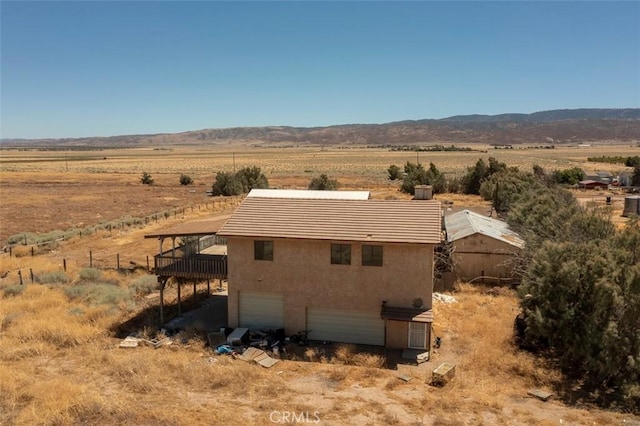 back of property featuring a rural view, a garage, and a mountain view