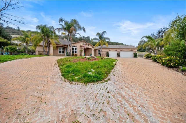 view of front of property with decorative driveway, an attached garage, and stucco siding