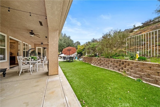 view of yard featuring outdoor dining space, ceiling fan, a patio, and fence