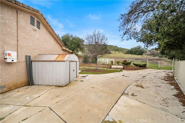 view of patio with an outbuilding, a fenced backyard, and a shed