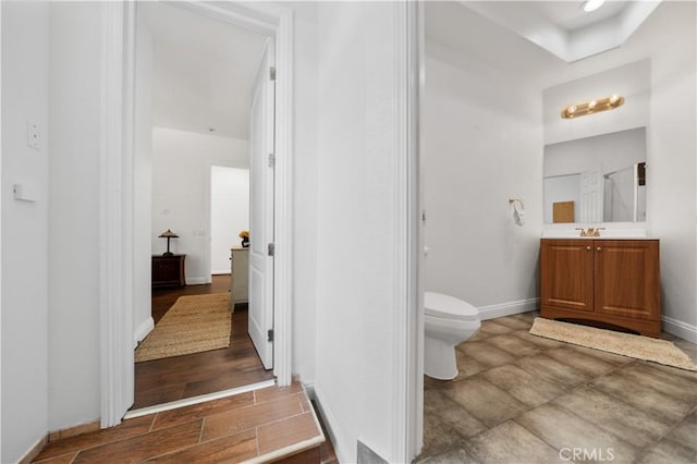 bathroom with toilet, baseboards, wood finished floors, and vanity