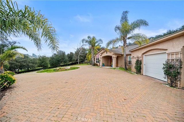 view of front facade with a garage, decorative driveway, and stucco siding