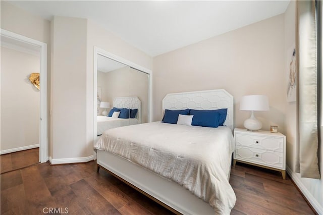 bedroom with a closet, baseboards, and dark wood-type flooring