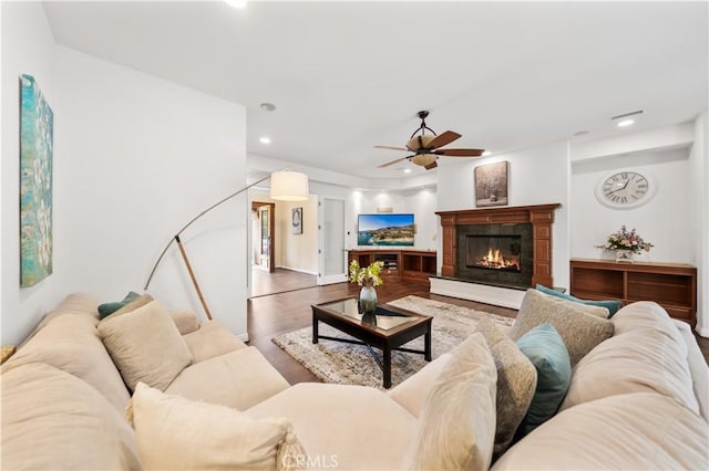 living area with recessed lighting, a glass covered fireplace, ceiling fan, and wood finished floors