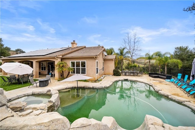 view of pool with a pool with connected hot tub, a patio area, and fence