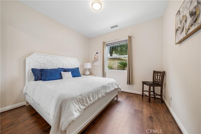 bedroom with dark wood finished floors, visible vents, and baseboards