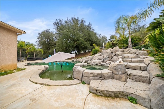 pool featuring a patio area, fence, and an in ground hot tub